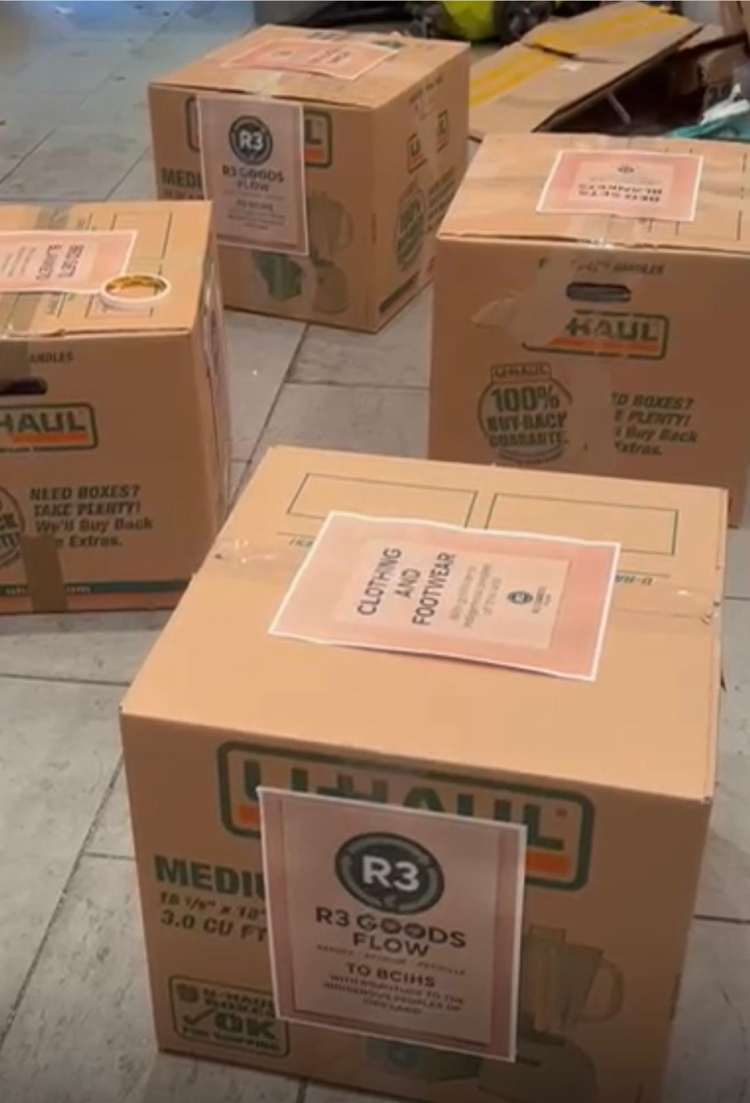 Multiple R3 Goods Flow U-Haul boxes with category labels including Clothing and Footwear, ready for distribution