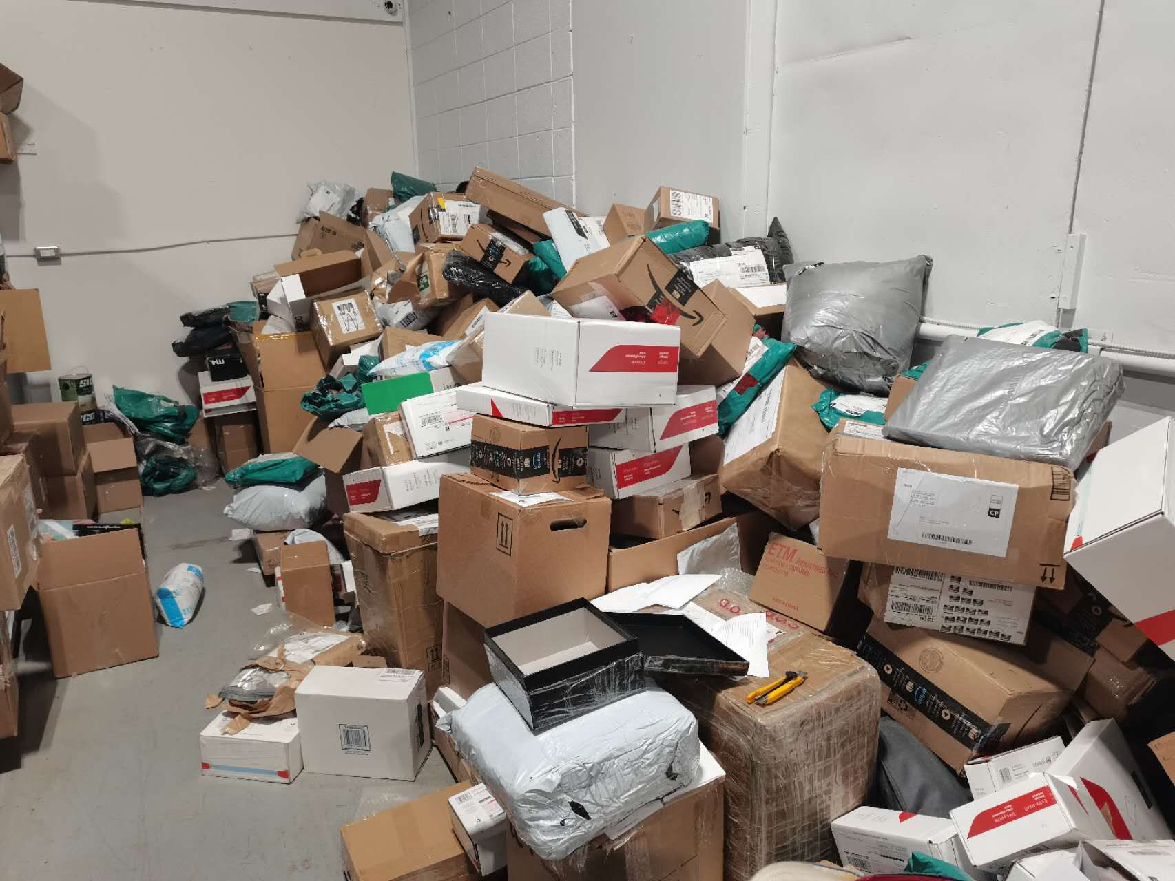 Large pile of returned e-commerce packages and boxes in warehouse sorting area